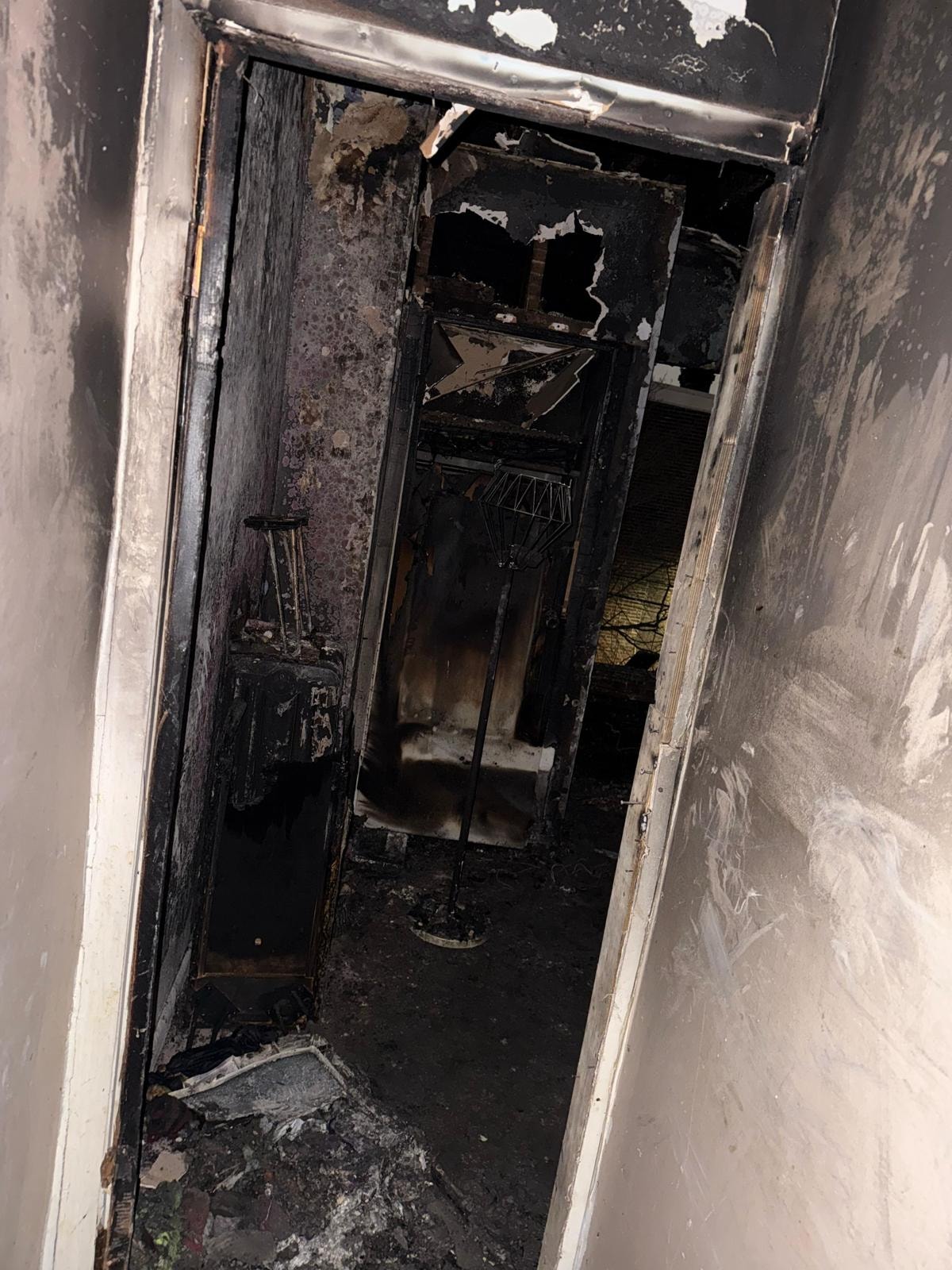 Fire-damaged interior hallway showing charred walls and debris in a Bensalem home