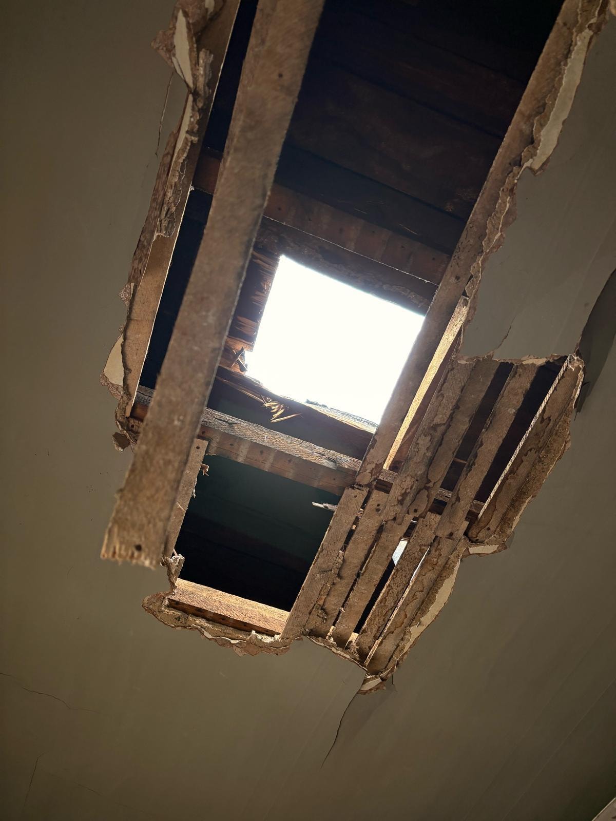 Collapsed ceiling with exposed structural beams showing severe property damage